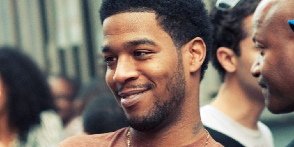 A close-up of Kid Cudi, looking off to the side, smiling.