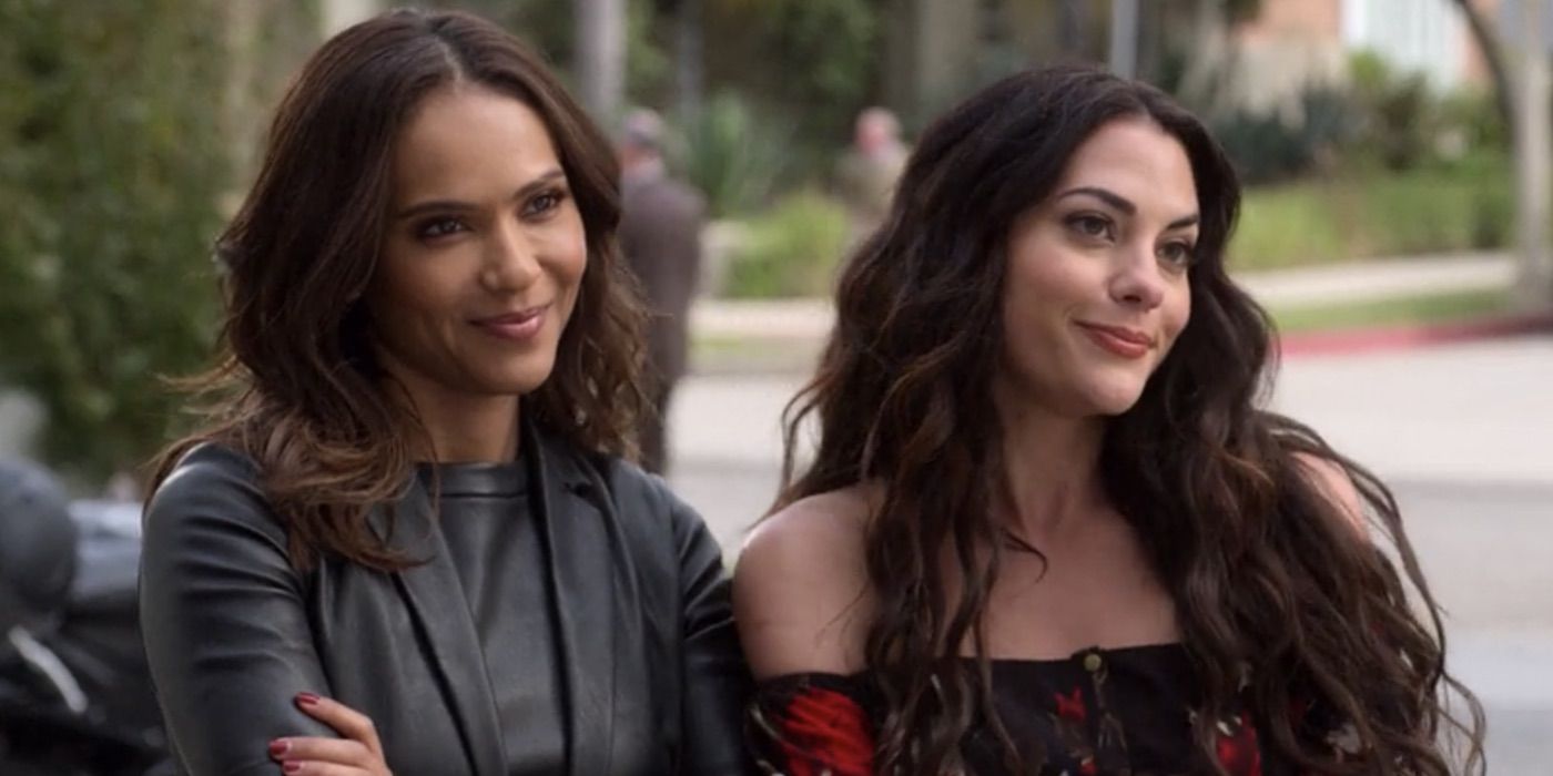 Maze and Eve from Lucifer standing together outside, both smiling.