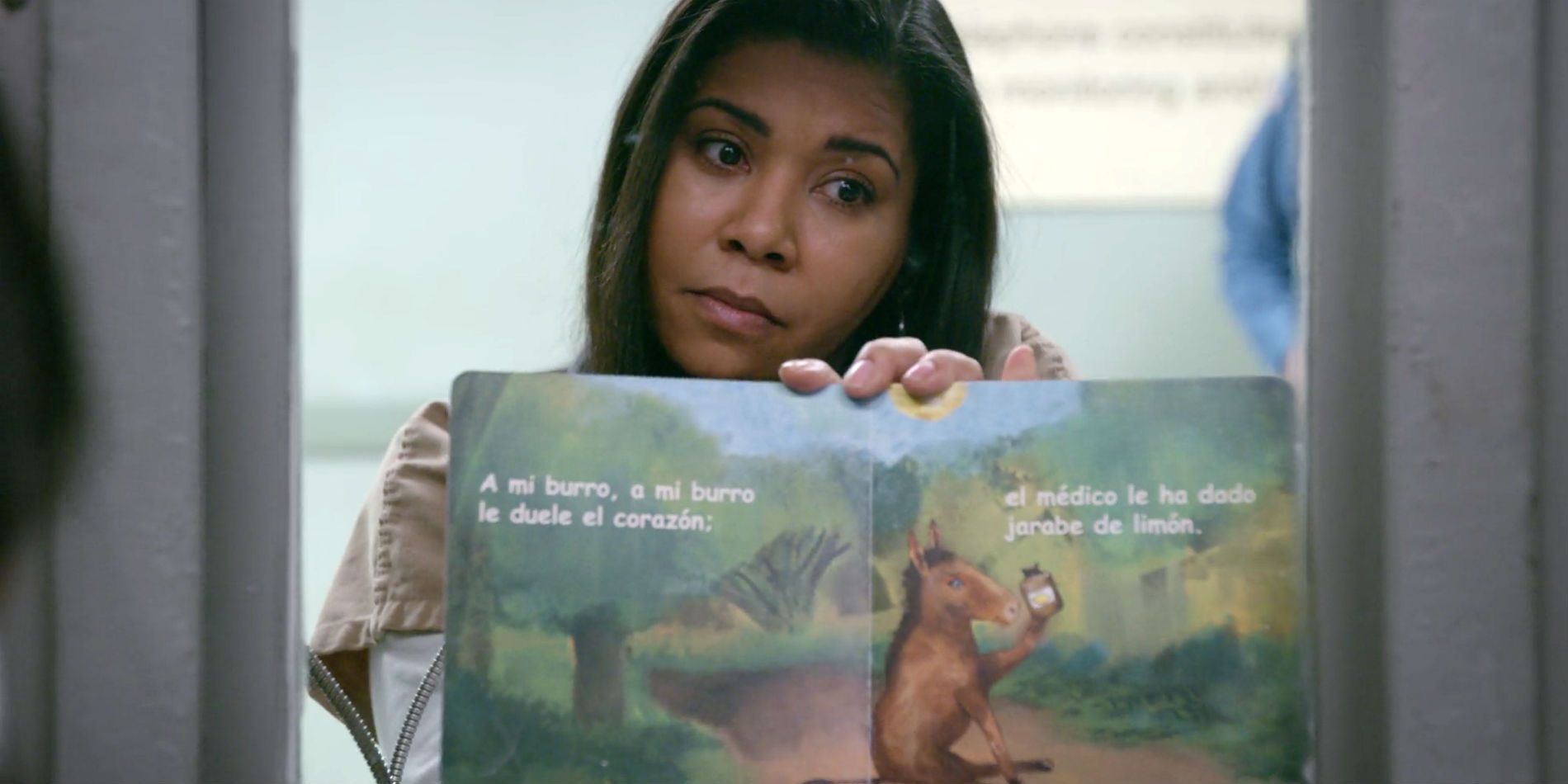 Ruiz holding up a book in Orange is the New Black.