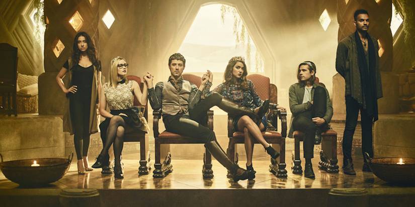 Alice, Eliot, Margo, and Quentin sit in their thrones with crowns on their heads while Julia and Penny stand next to them.
