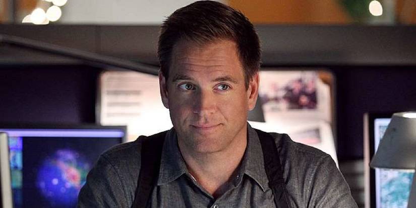 Tony DiNozzo smiling in front of multiple monitors in NCIS