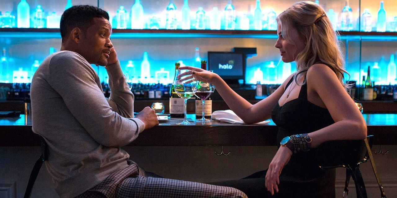 Will Smith and Margot Robbie sitting at the bar and looking at each other in Focus