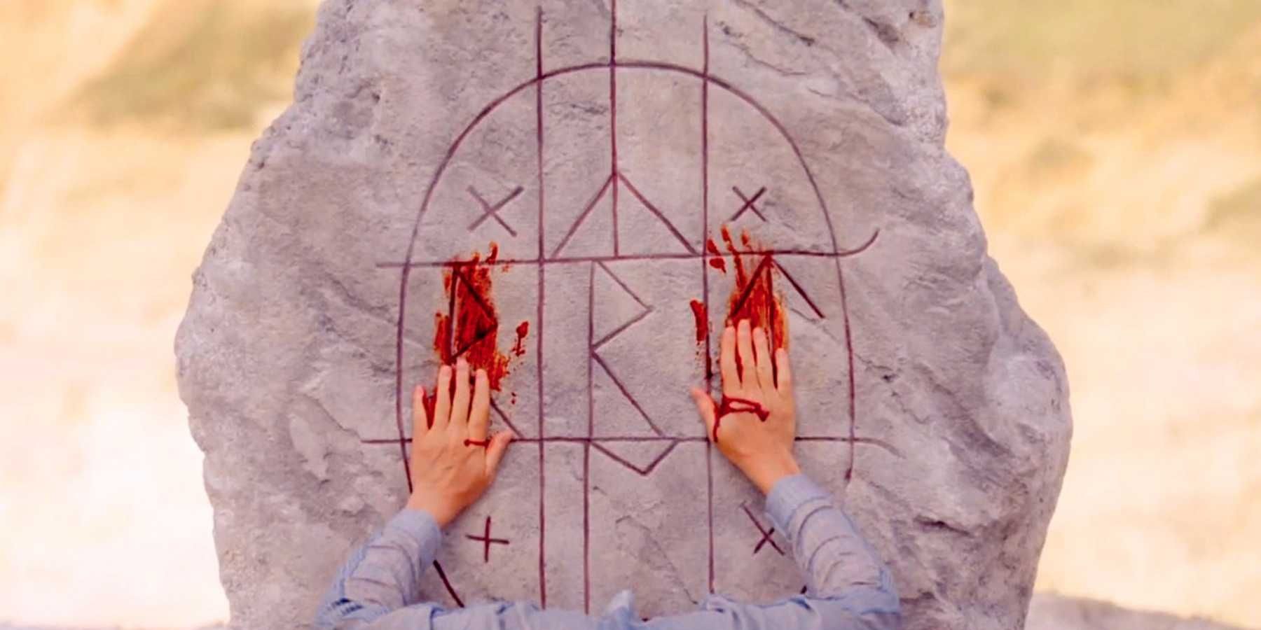 Bloody hands on a runic symbol in Midsommar