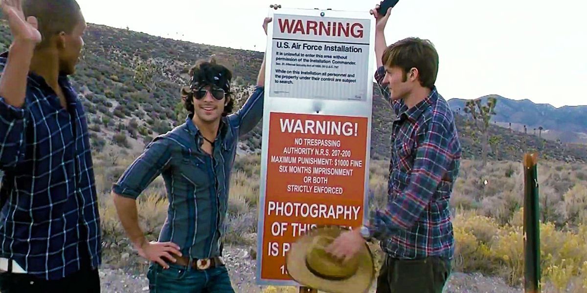 The characters standing outside next to a sign in Area 51