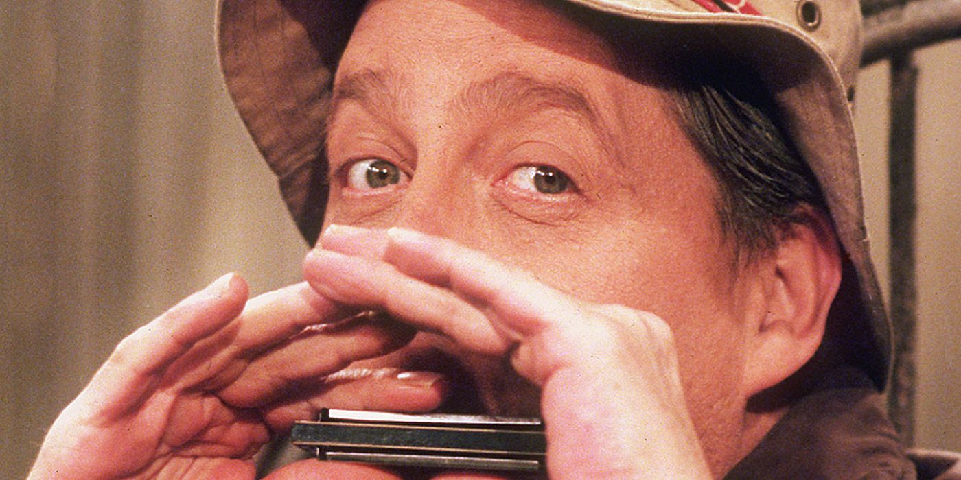 Wilson hides his face by playing a harmonica in Home Improvement