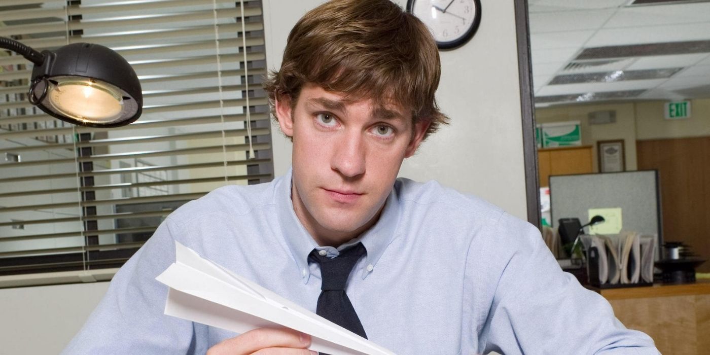 Jim holding a paper airplane looking at the camera on The Office