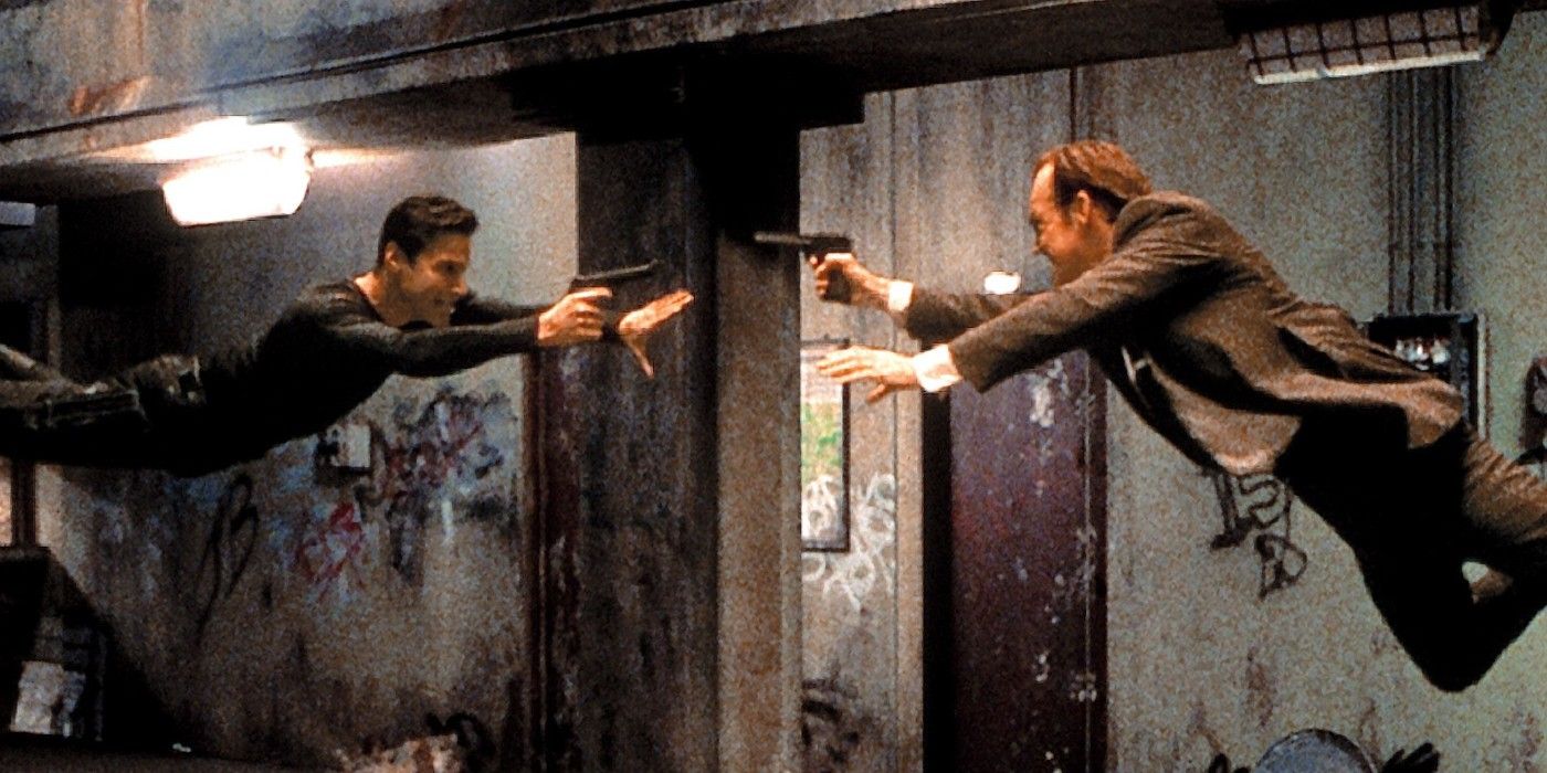 Keanu Reeves as Neo and Hugo Weaving as Agent Smith leap at each other with guns drawn.