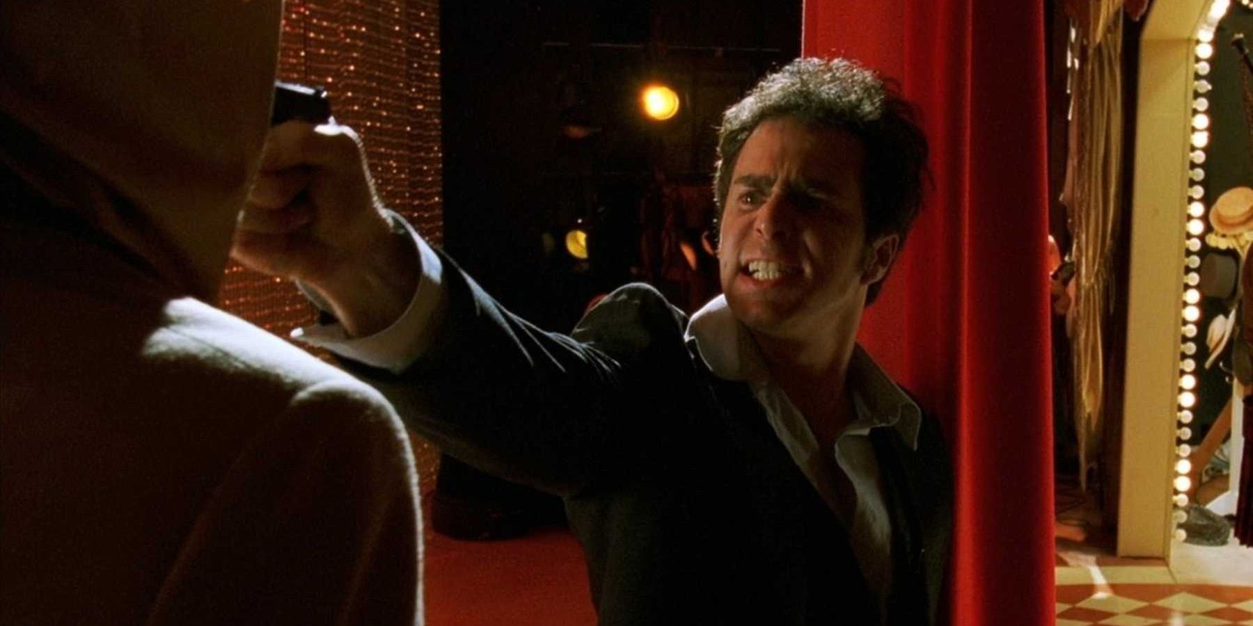Chuck points a gun behind the stage in Confessions of a Dangerous Mind