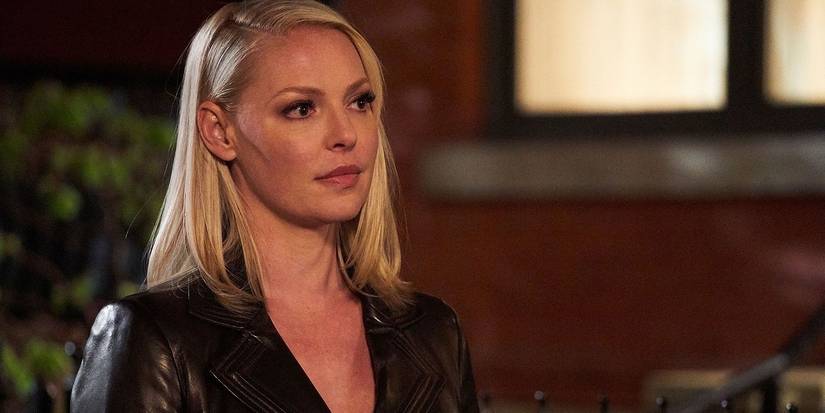 Samantha Wheeler from Suits wearing a low-cut black top, hair behind her ear.
