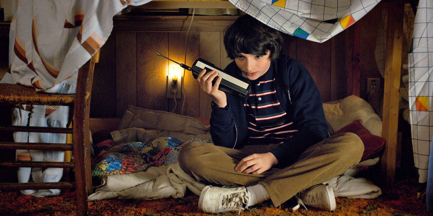Mike sits in the sleeping area made for Eleven with his walkie talkie in Stranger Things