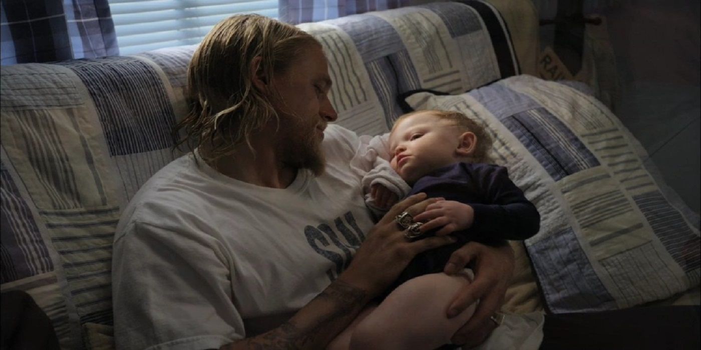 Jax holding his baby boy on the sofa in Sons of Anarchy