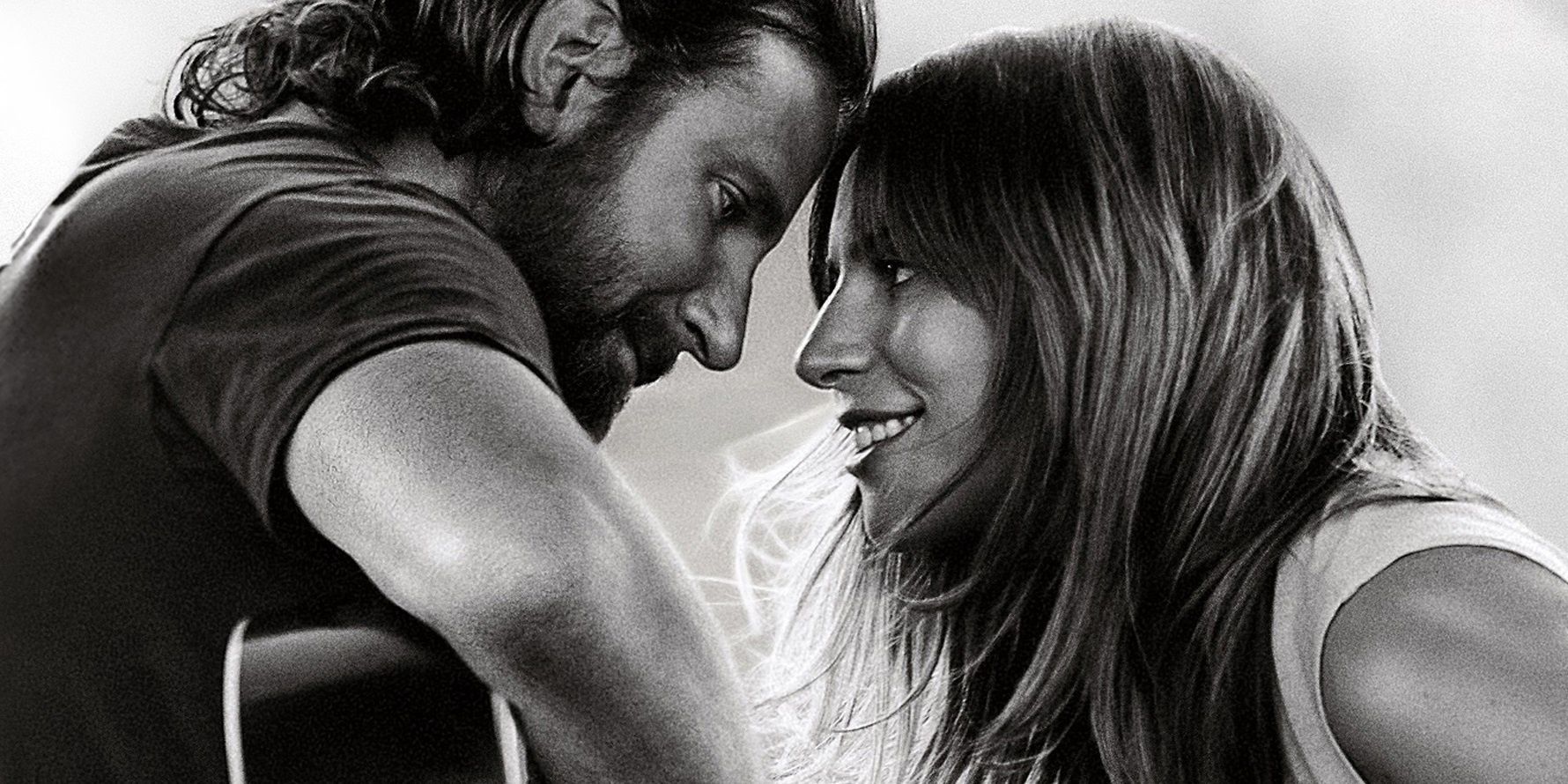 Lady Gaga and Bradley Cooper in A Star is Born, ​sitting close intimately playing guitar.