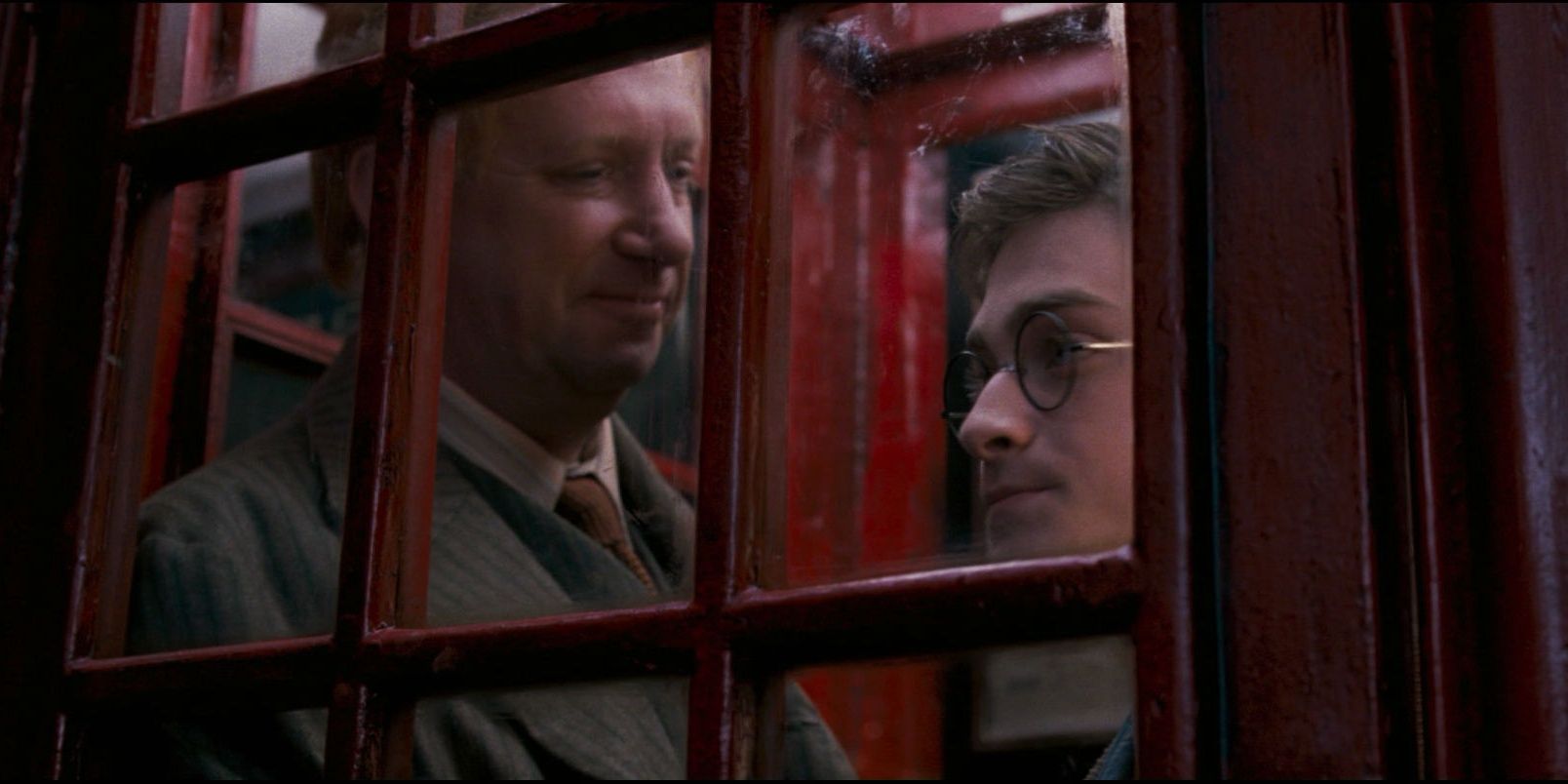 Harry and Arthur Weasley standing in a phone booth in Harry Potter. 
