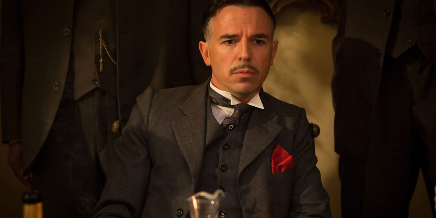 Billy Kimber sits at a table in Peaky Blinders.
