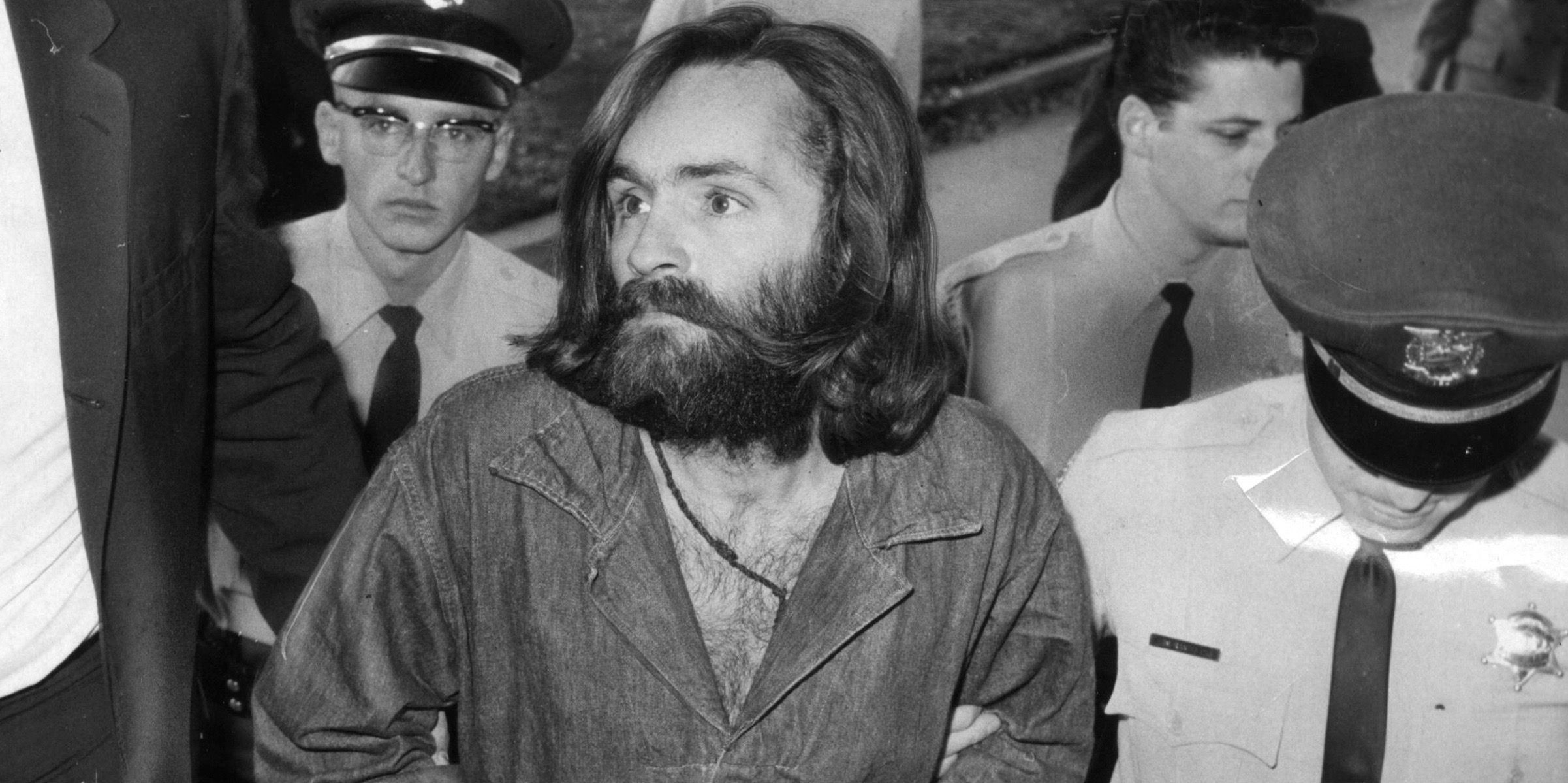 Charles Manson being escorted by police in real life black and white photo