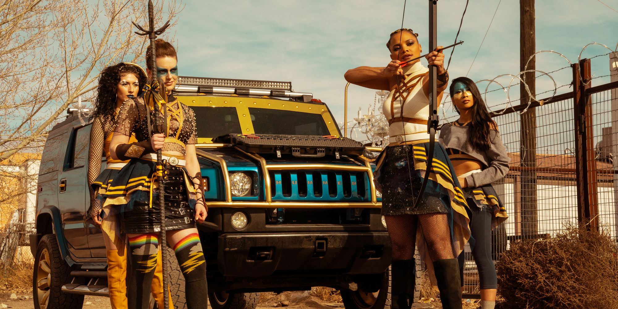 Characters wearing warpaint and holding weapons stand in front of an armored Hummer in Daybreak