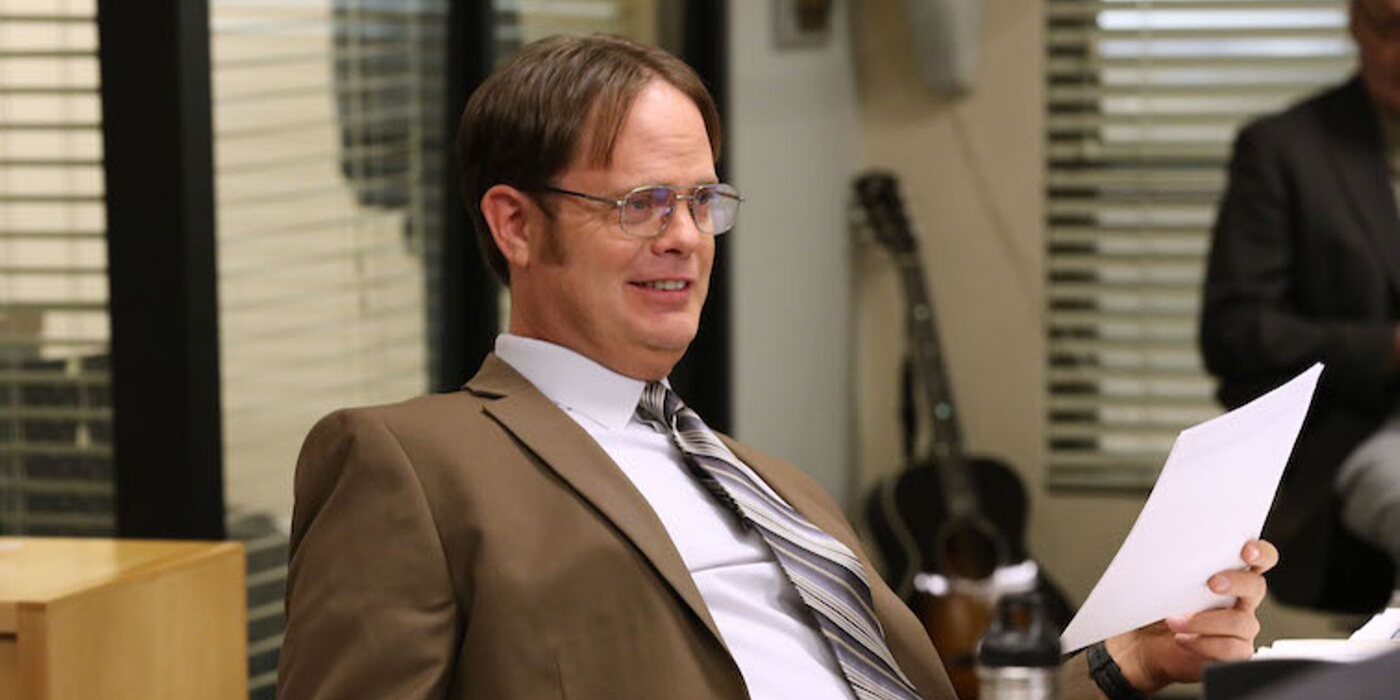 Dwight sitting at his desk and smiling in The Office