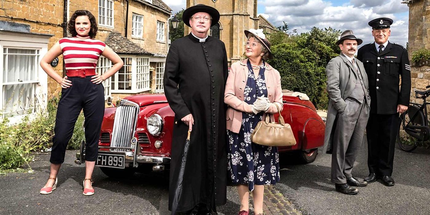 Cast of Father Brown posing in front of a car for a promo photo
