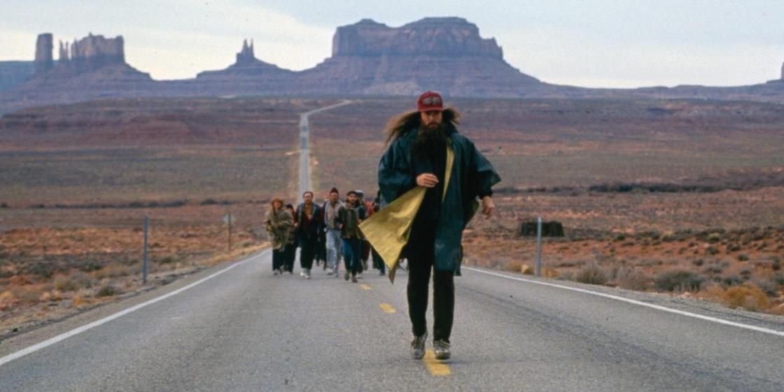 Forrest Gump Correndo em uma estrada com uma multidão atrás dele e o Grand Canyon à distância