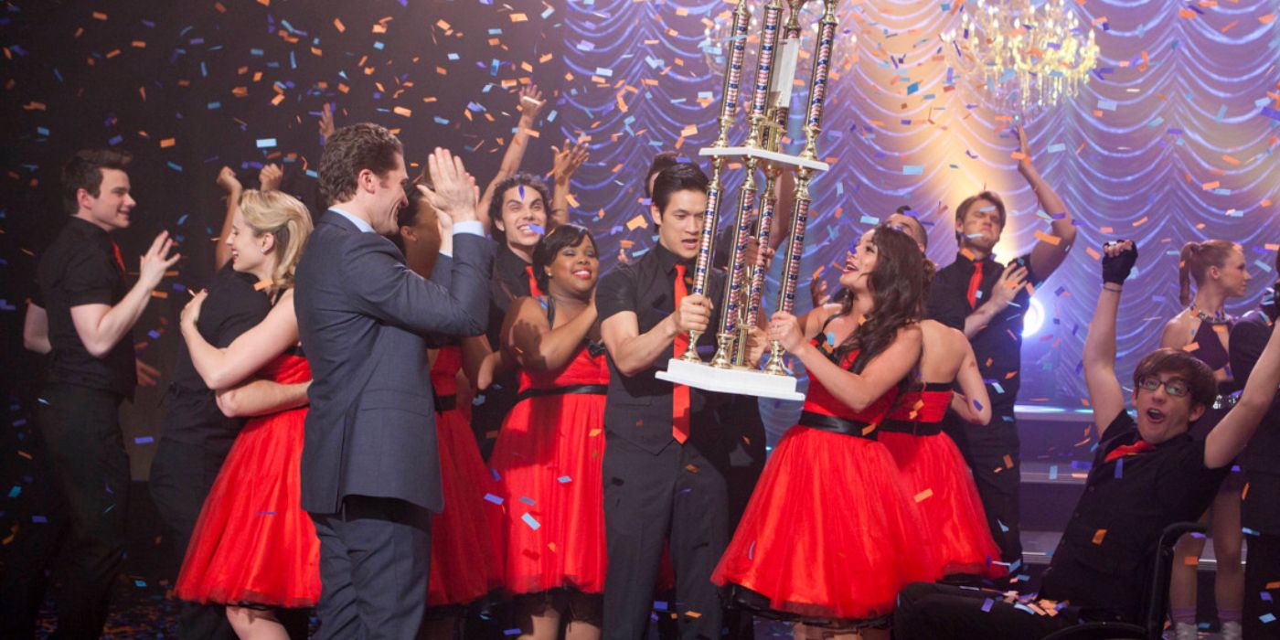 Glee's The New Directions hold a trophy onstage as confetti falls down