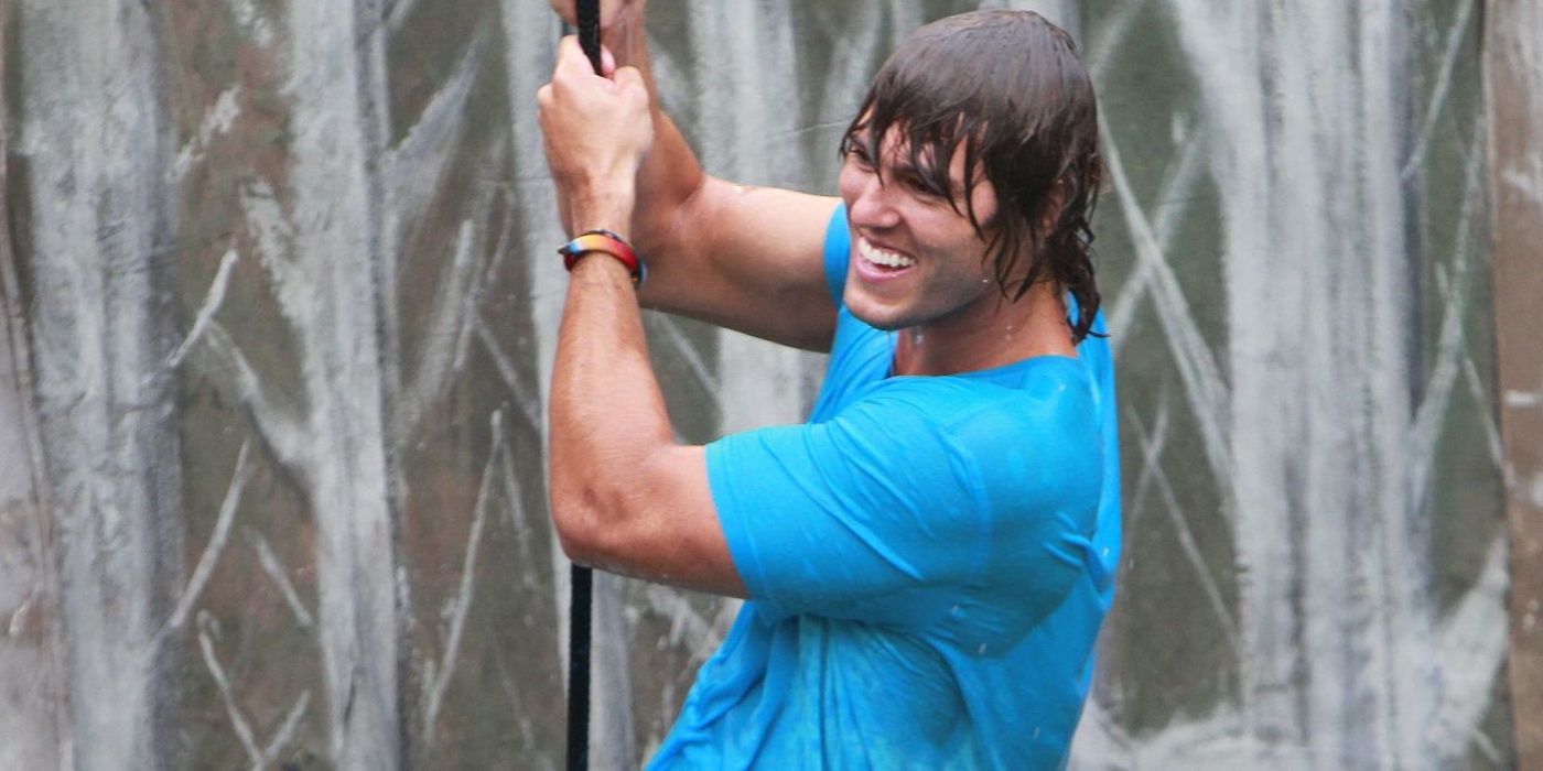 Hayden from Big Brother, holding on to a rope and soaking wet.