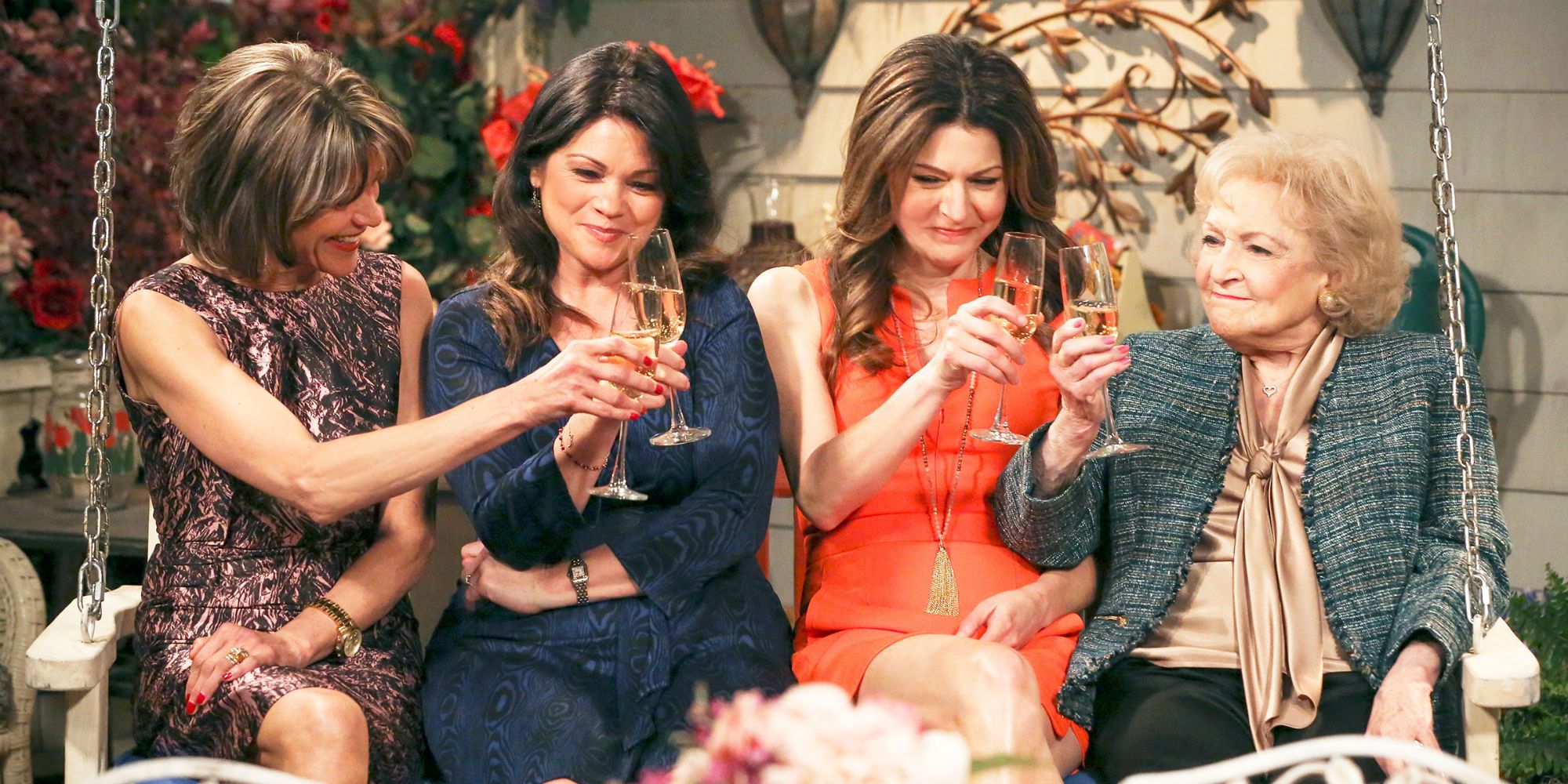 The cast of Hot In Cleveland toasting on a porch swing