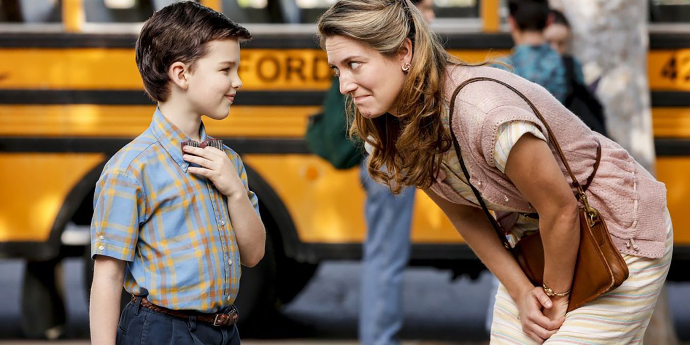 Sheldon sorrindo para sua mãe na frente do ônibus escolar em uma cena de Young Sheldon.