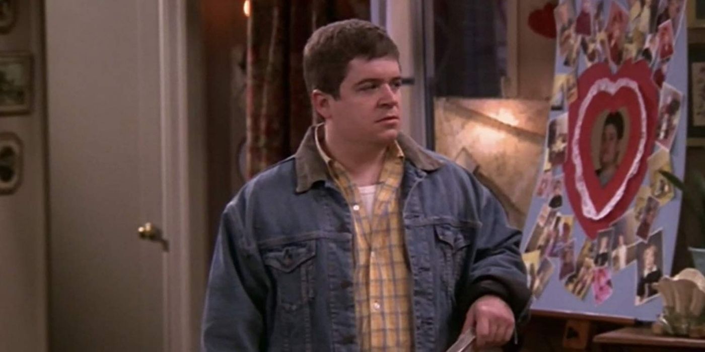 Patton Oswalt standing silently in Doug's living room in The King of Queens
