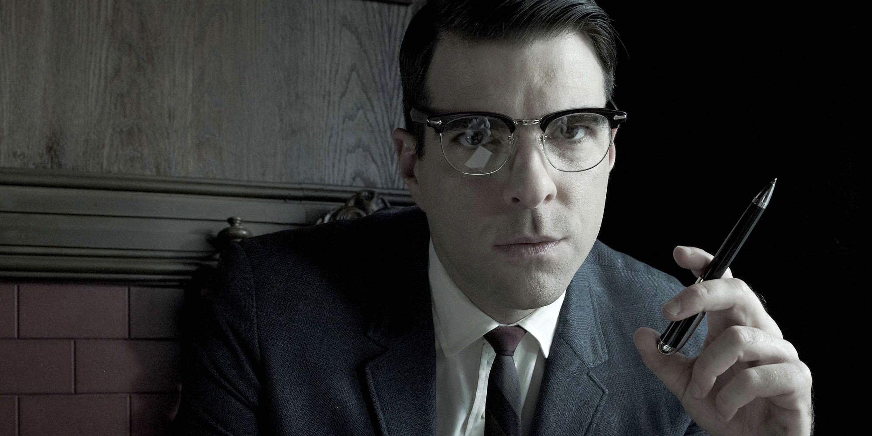 Oliver Thredson holds a pen and looks at something in American Horror Story