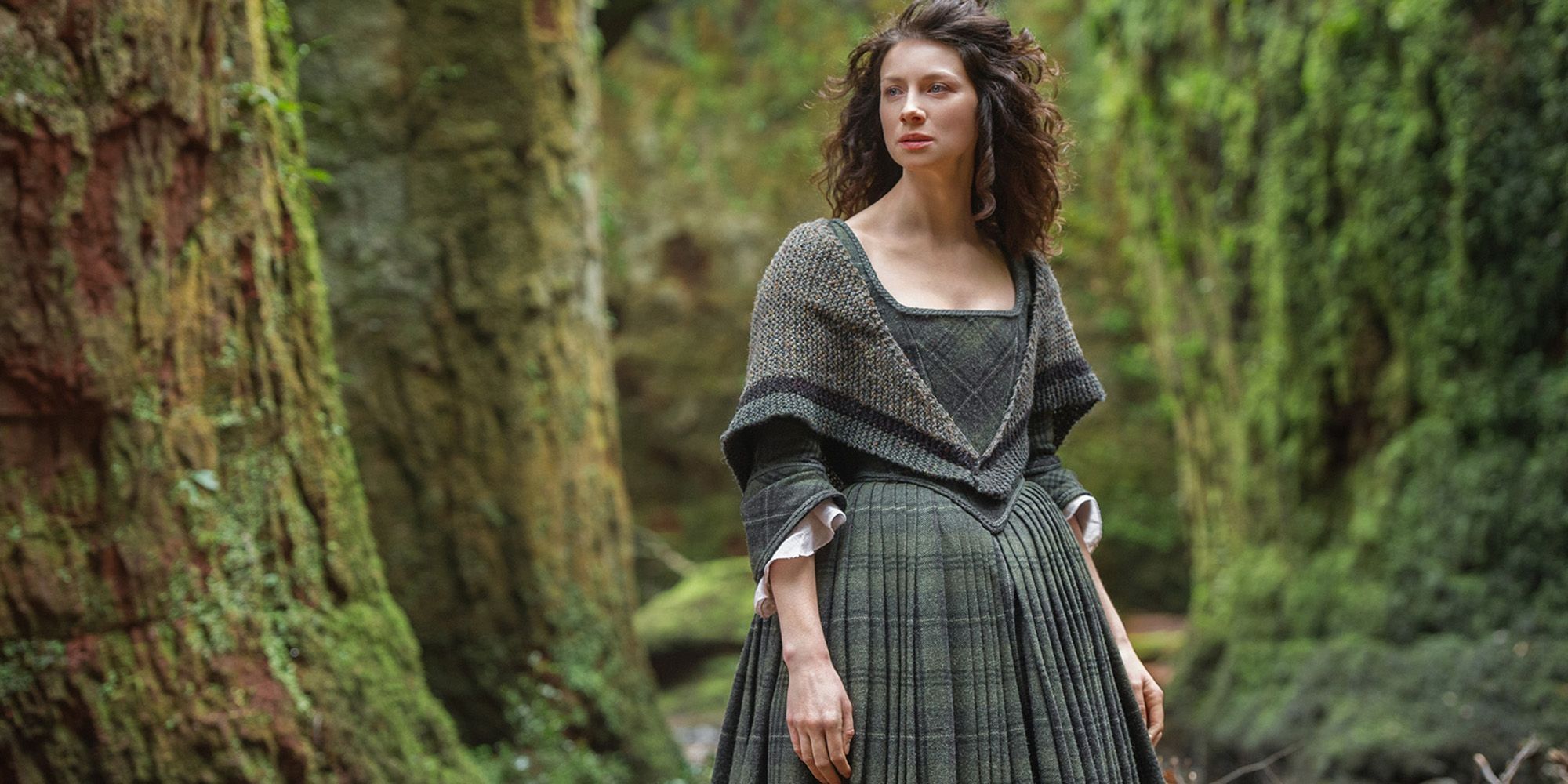 Claire stands in the woods in Outlander