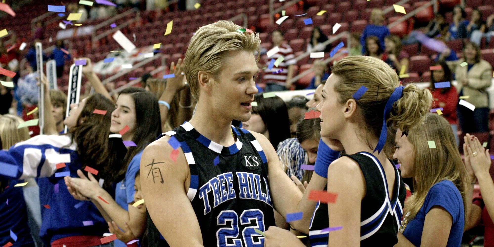 Lucas and Peyton smiling at each other at a basketball game on One Tree Hill