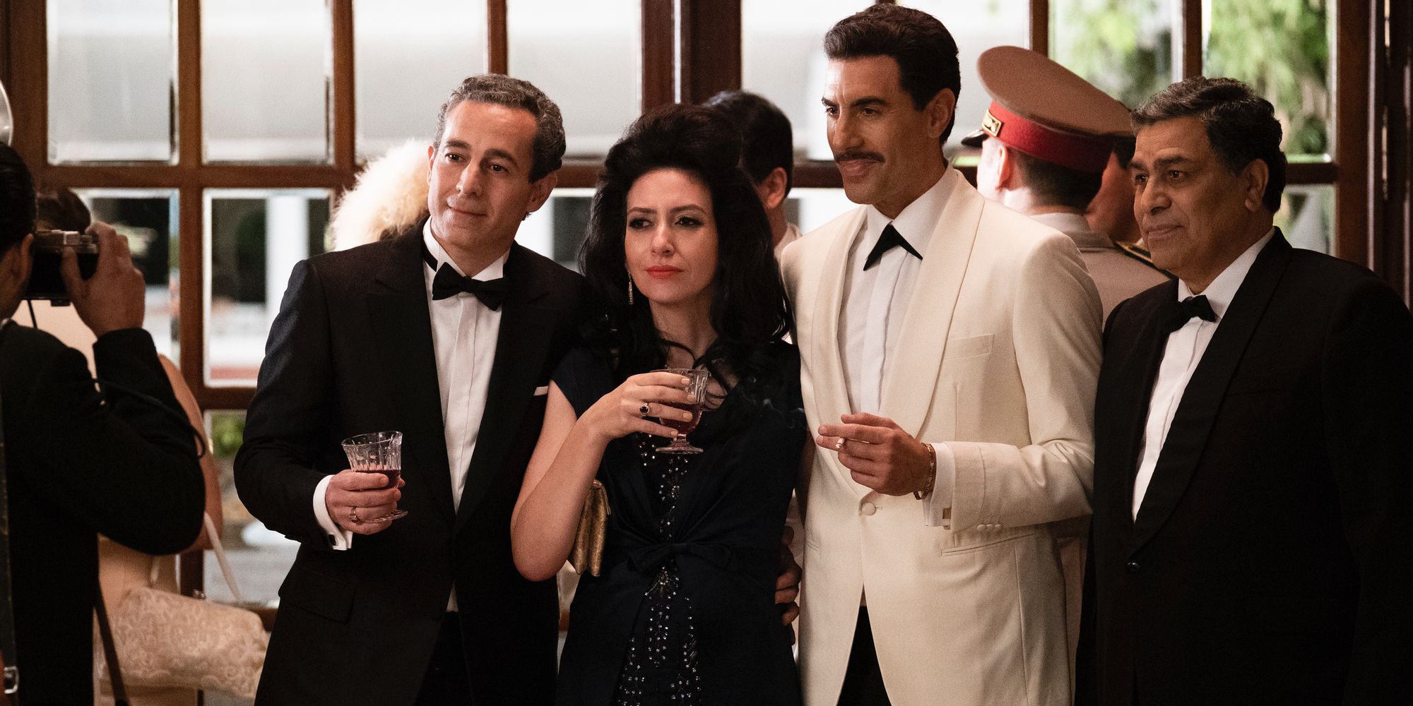 Sacha Baron Cohen as Eli Cohen posing with other characters in The Spy Netflix