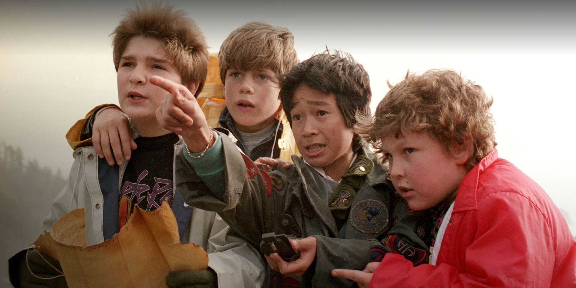 Mouth, Mikey, Data, and Chunk examining the map and something in the distance in The Goonies