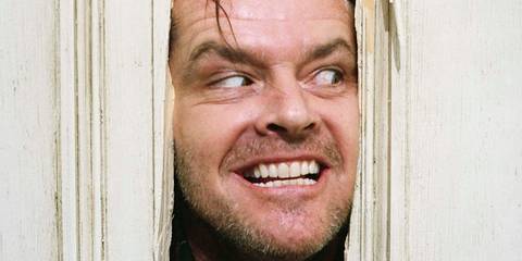 Jack Torrance (Jack Nicholson) grinning through a broken door in The Shining
