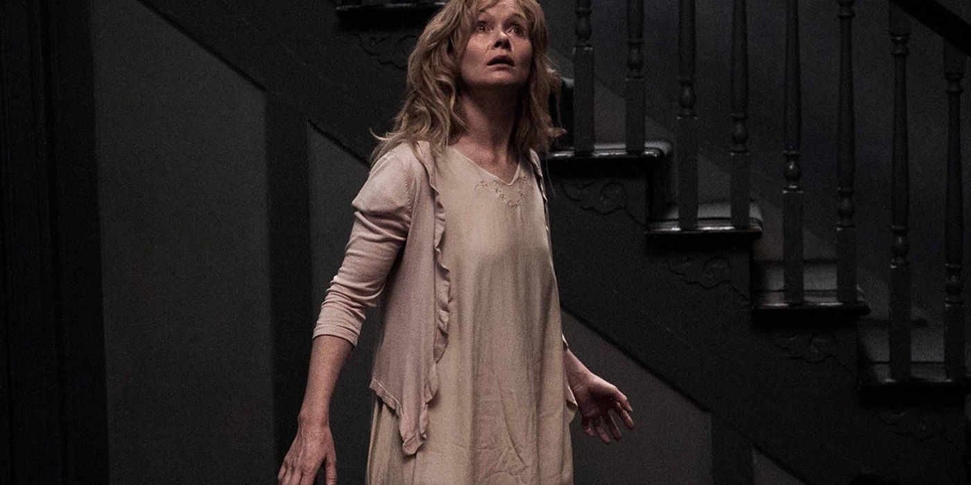 Essie Davis looking scared standing by the stairs in The Babadook