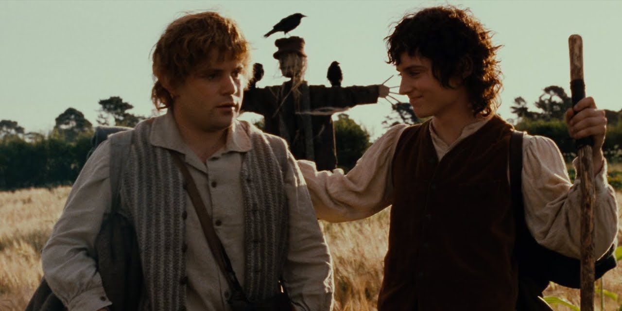 Frodo coloca o braço em volta de Sam em um campo com um espantalho ao fundo no início de O Senhor dos Anéis A Sociedade do Anel
