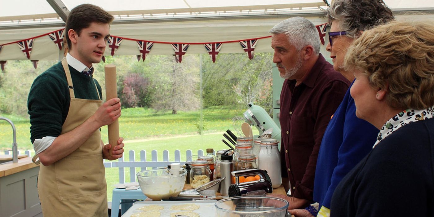 A contestant speaks with the judges from Great British Bake Off