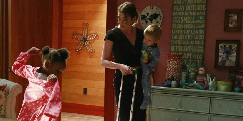 Meredith and Zola inside her house. Meredith is seen to be holding Bailey and a suitcase. She is also watching Zola put on her pink coat