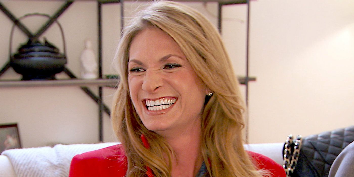 Heather Thomson RHONY smiling on couch in red outfit