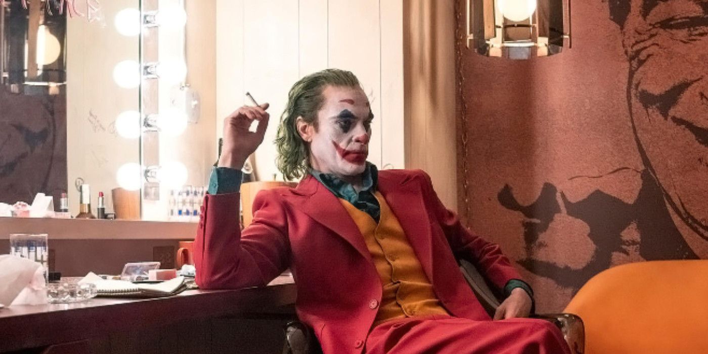 Arthur smokes in his clown make up and costume in Joker