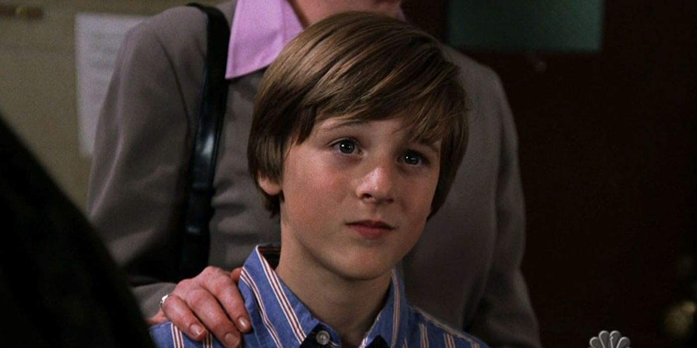 A young boy smirks with a woman's hand on his shoulder in the Law and Order SVU episode Conscience