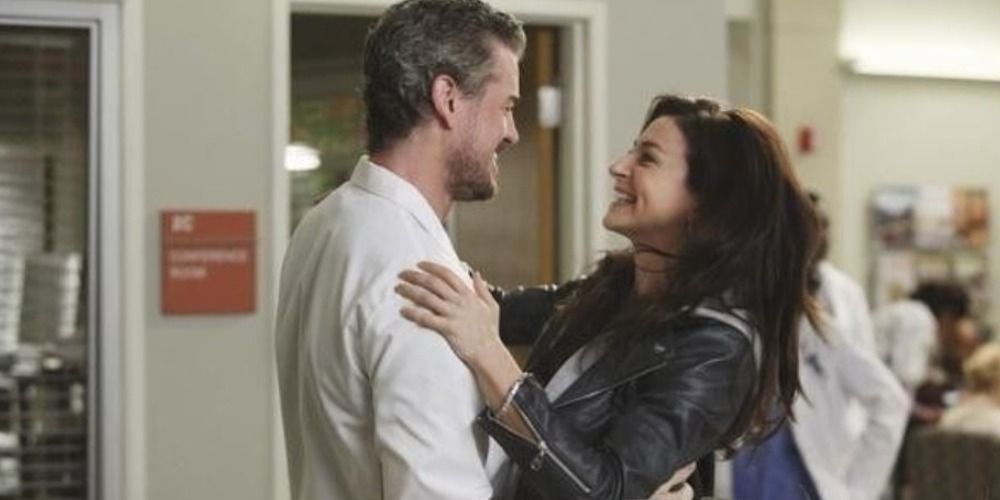 Mark Sloan and Amelia Shepherd embracing and smiling in the hospital hallway in Grey's Anatomy