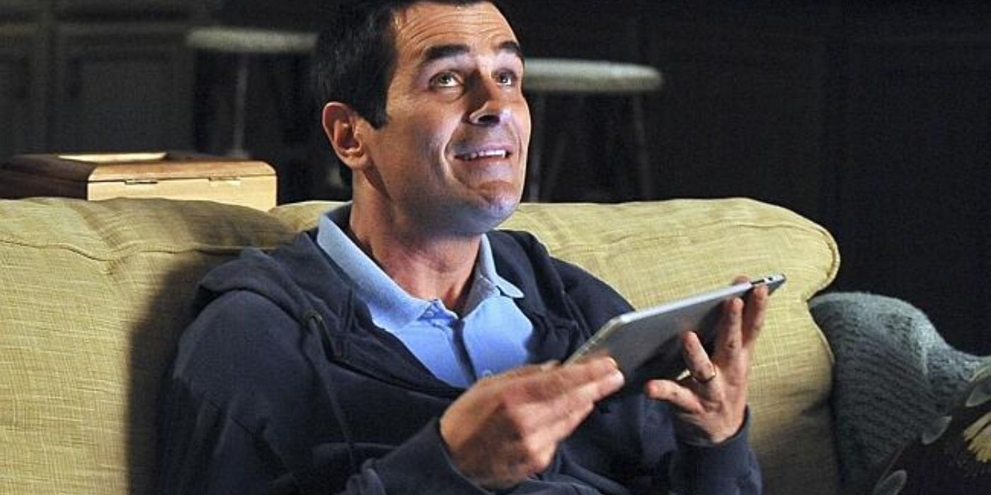 Phil sonriendo mientras usa su iPad en Modern Family