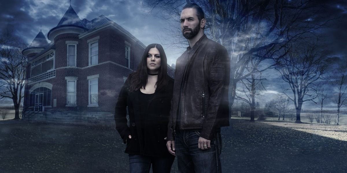 Two ghost hunters pose in front of a spooky building from Paranormal Lockdown 