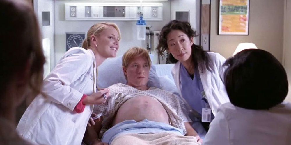 Cristina and Izzie takes pictures with the patient who believed he was pregnant