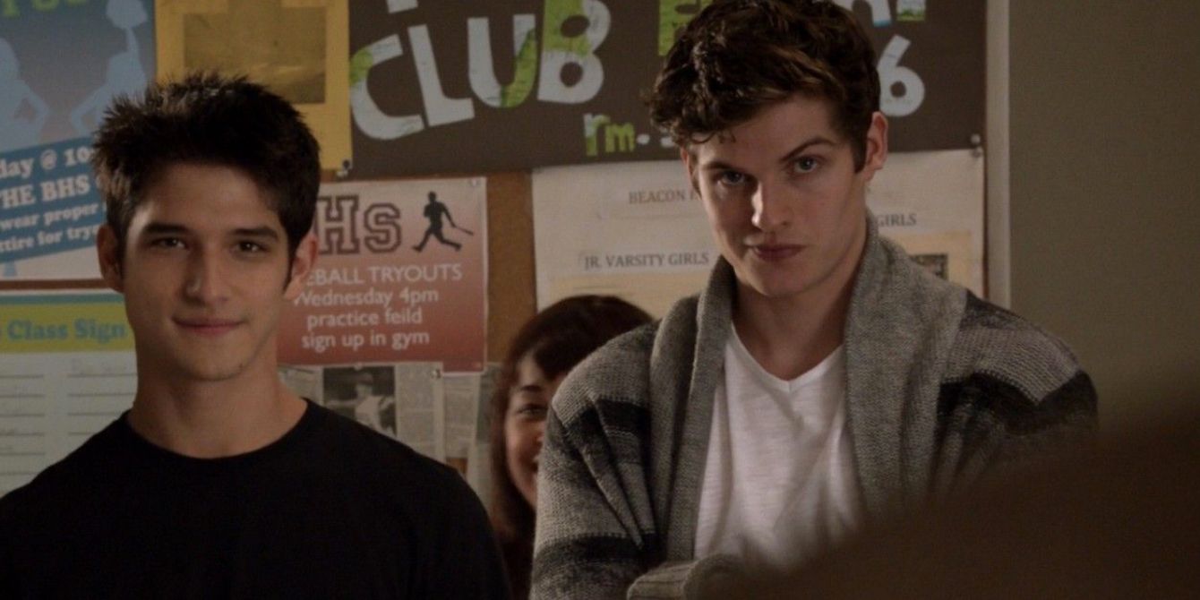 Scott and Isaac look at their classmates in a high school hallway in Teen Wolf.