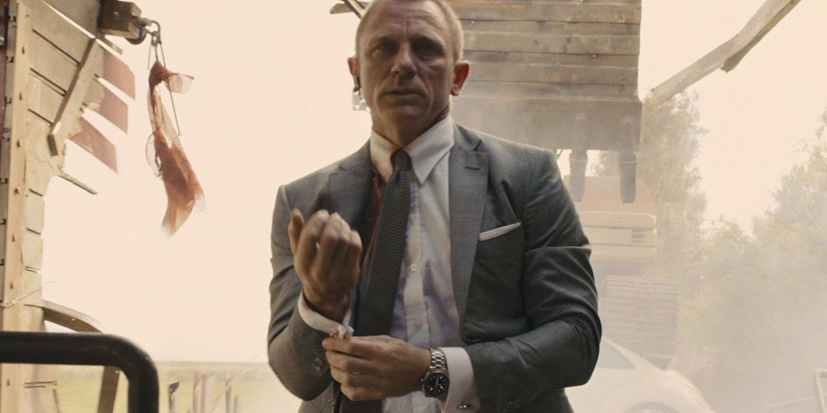 James Bond checks his cufflinks while a train crashes behind him in Skyfall.