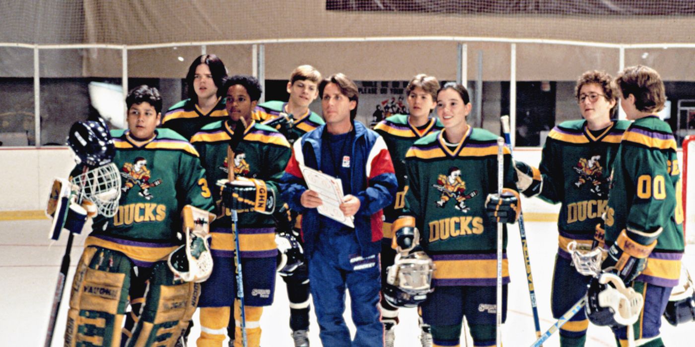 Coach Bombay standing with a clipboard in front of the Mighty Ducks team before new members are added in D2