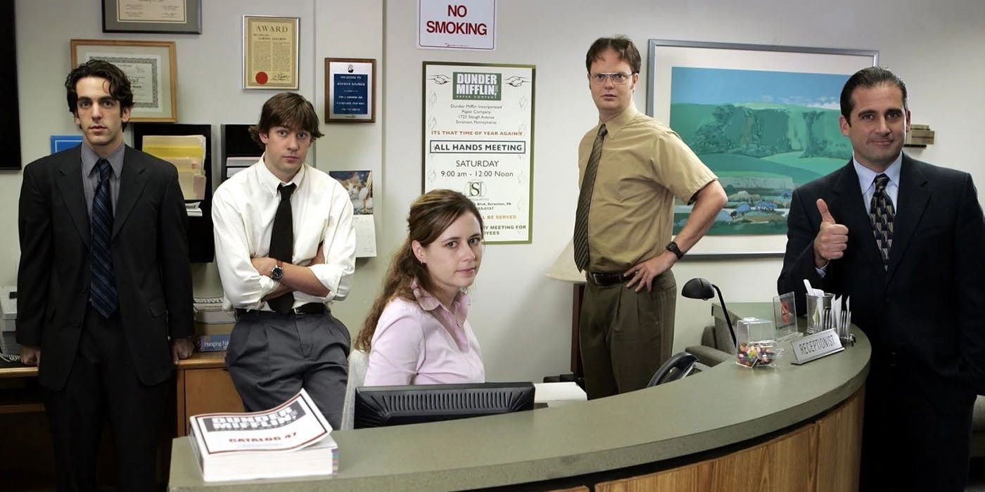 An image of The Office cast members standing together in the workplace