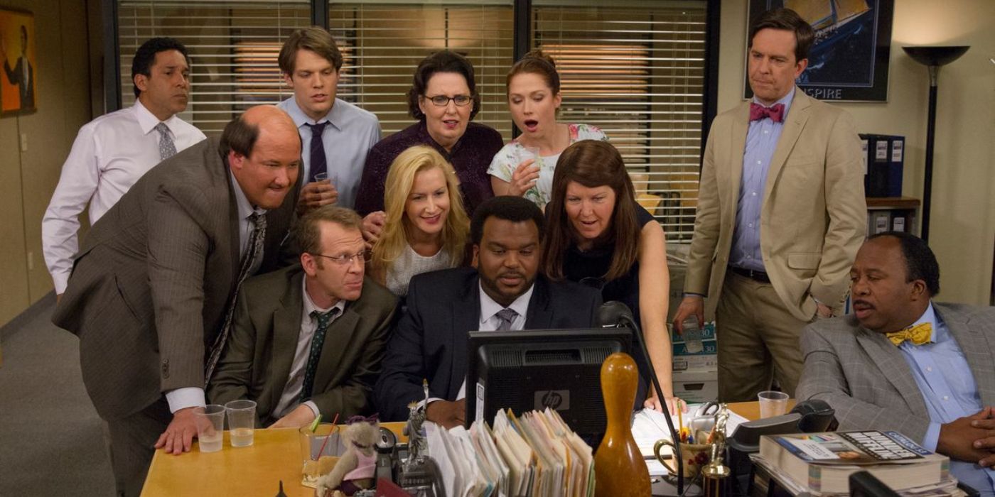 The Office cast standing together and looking at a computer in The Office